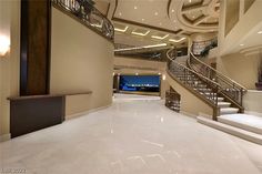 a large foyer with white marble flooring and stairs leading up to the second story