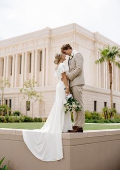 a bride and groom kissing in front of the stately building at their wedding reception