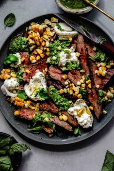 a plate filled with steak, broccoli, corn and feta cheese on top