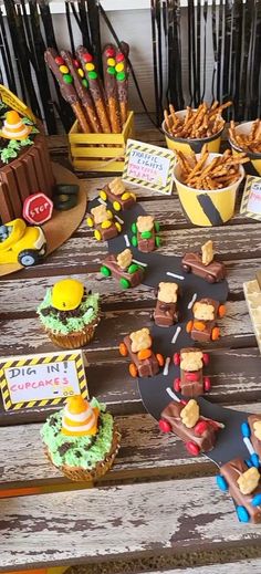 a wooden table topped with lots of cupcakes and desserts on top of it