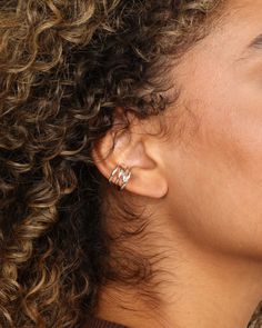 a close up of a person with curly hair and ear piercings on their ears