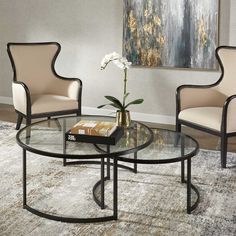 a living room with two chairs and a coffee table in front of a painting on the wall