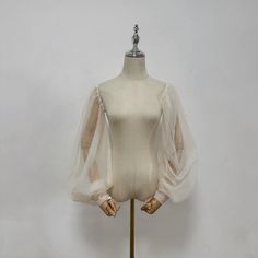 a mannequin wearing a white dress with sheer sleeves on it's shoulders