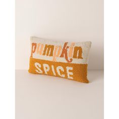 an orange and white pillow with the words pumpkin spice on it, sitting on a table