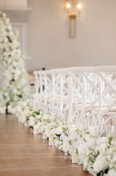 rows of white chairs lined up with flowers and candles on the floor in front of them