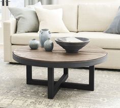 a coffee table with two vases on it in front of a couch and window