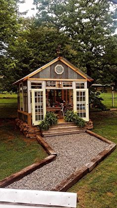 a small garden shed in the middle of a yard with gravel and rocks around it