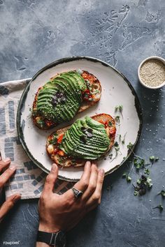 two pieces of toast topped with avocado on top of a white plate