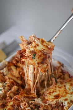 a close up of a person holding a fork with food on it in a dish