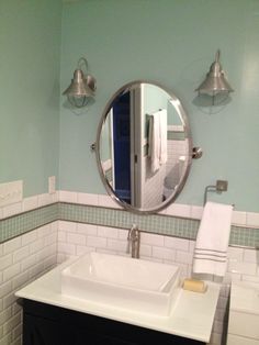 a bathroom sink sitting under a round mirror