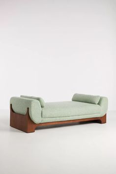 a green chaise lounge chair sitting on top of a white floor next to a wall