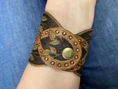 "\"Meliae\" a tooled leather bracelet with bright green sea sediment jasper cabochon and colorful leaves. It reminds me about old times of witches, dryads, druids, elves, fairies and other creatures who lived in harmony with Mother Earth. The cuff was made to fit a 7\" wrist. 👆 NB❗️❗️❗️I HIGHLY recommend choosing PAYPAL payment option! Items paid by any method other than PayPal will take longer to become available, for all other options are slower. I also have to note that I'm not responsible f Handmade Adjustable Nature-inspired Cuff Bracelet, Green Leather Artisan Jewelry, Handmade Green Leather Bracelet, Green Bohemian Bracelets With Patina, Bohemian Hand Tooled Green Jewelry, Bohemian Adjustable Carved Bracelets, Adjustable Bohemian Carved Bracelets, Adjustable Bohemian Carved Bracelet, Handmade Earthy Leather Bracelet For Gift