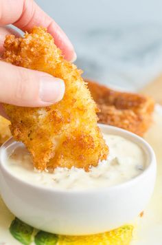 a person dipping something into a small white bowl