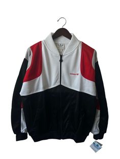 "80s adidas track jacket. black, white, & red. side pockets. metal logo zipper pull. embroidered logo on chest. 26\" long. 24.5\" across. 27\" sleeves. in excellent, unworn condition. legit. legitvintage.etsy.com legitvintage on instagram" White Long Sleeve Track Jacket With Adidas Logo, White Long Sleeve Adidas Track Jacket, Adidas Long Sleeve Track Jacket, Adidas Track Jacket With Logo For Fall, Retro Track Jacket With Three Stripes For Streetwear, Retro Streetwear Track Jacket With Three Stripes, Streetwear Long Sleeve Windbreaker With Three Stripes, Crew Neck Outerwear With Three Stripes For Streetwear, Coveralls Mens