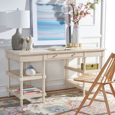 a white desk topped with a vase filled with flowers next to a chair and lamp