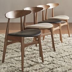 four wooden chairs sitting on top of a rug