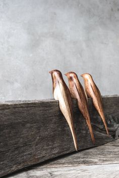 three wooden birds sitting on top of a piece of wood