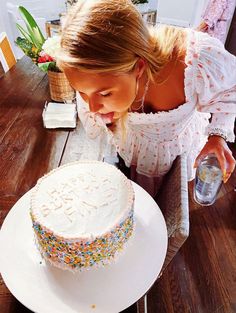 a woman is blowing out the candles on her birthday cake while sitting at a table