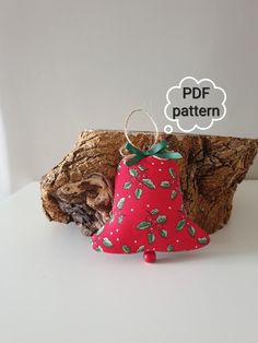 a red bell ornament sitting on top of a piece of wood with a thought bubble above it