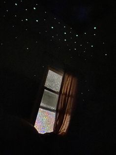 a window in the dark with glow stars on it's ceiling and curtains open