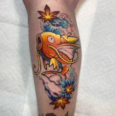 a tattoo on the leg of a person with an orange fish and flowers around it