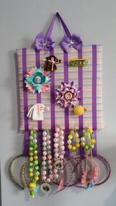 a purple and white striped wall hanging with lots of hair accessories on it's side