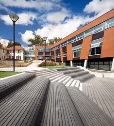 an empty bench in front of a building with stairs leading up to the top floor