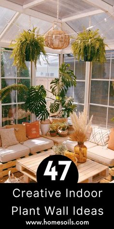 a living room filled with lots of plants next to a white couch and table in front of large windows