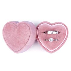 two pink velvet heart shaped boxes with wedding rings in them, one has a diamond ring