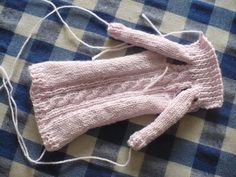 a pink knitted sweater laying on top of a blue and white checkered table cloth