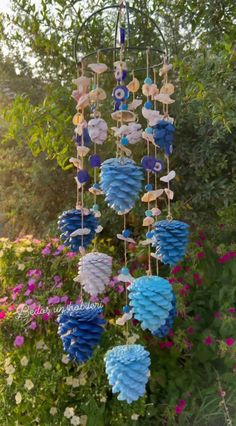 a wind chime hanging from the side of a tree in front of some flowers