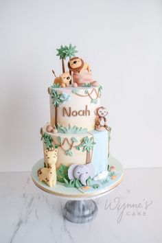 a three tiered cake decorated with animals and palm trees is on top of a marble stand