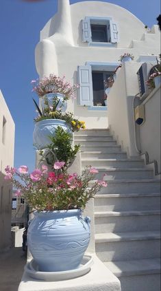 two large vases filled with flowers sitting on the side of a set of stairs