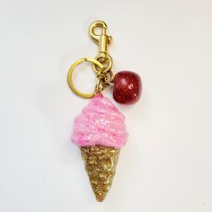 a key chain with a pink ice cream cone and a red glitter ball on it