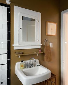 a white sink sitting under a bathroom mirror next to a wall mounted faucet