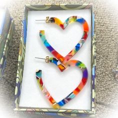 two colorful heart shaped earrings in a box