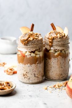 two mason jars filled with apple pie overnight oatmeal next to an apple