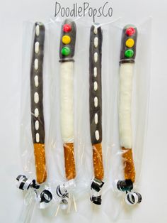 three decorated candy sticks in plastic wrappers on a white surface with the words doodle pops written above them