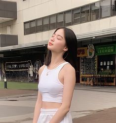 a woman standing in front of a building with her eyes closed