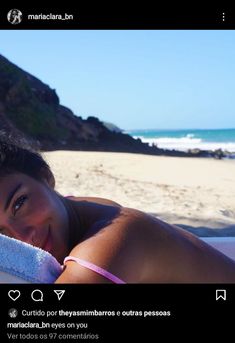 a woman laying on top of a beach next to the ocean with a towel around her neck