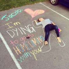 a woman laying on the ground with chalk writing in front of her and a car parked behind her