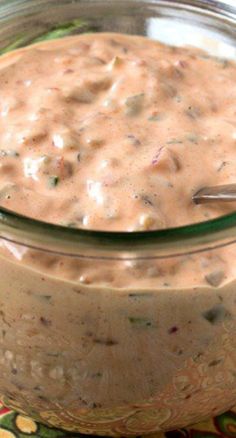 a glass jar filled with food sitting on top of a colorful table cloth next to a metal spoon