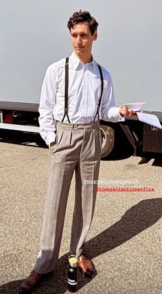 a man standing in front of a truck wearing suspenders and a white shirt with black tie