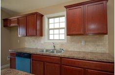 an empty kitchen with granite counter tops and wooden cabinets in the corner, along with a blue dishwasher