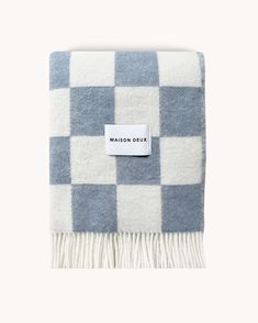 the blue and white checkered blanket has a tag on it that says maison dux