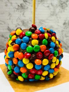 there is a chocolate covered apple with candy candies on it and a wooden stick sticking out of the top