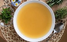 a bowl of soup is sitting on a table with flowers and spoons next to it