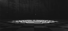 a black and white checkered floor with lights shining in the dark room behind it