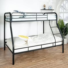 a metal bunk bed sitting on top of a hard wood floor next to a potted plant