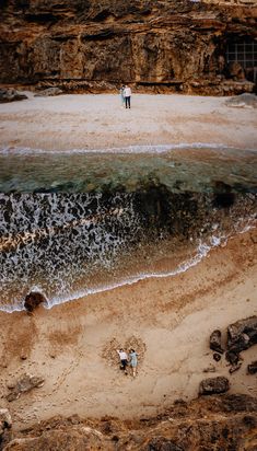 two people are standing on the beach by the water